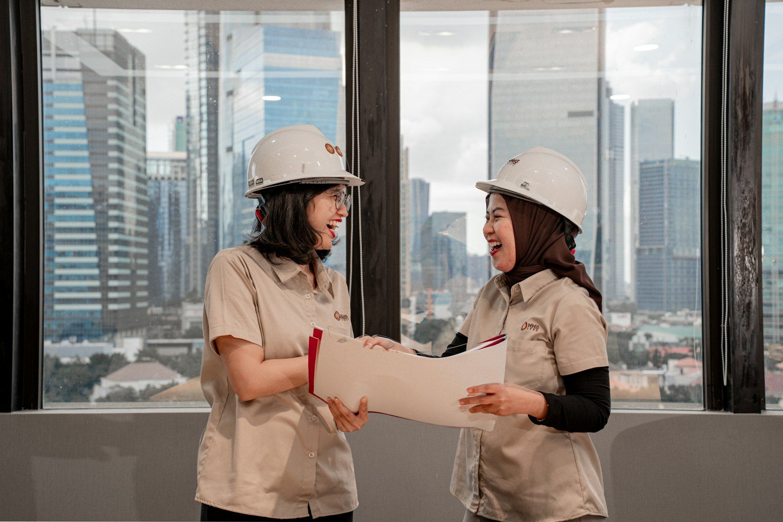 Due tecnici con casco da cantiere controllano le planimetrie di un progetto